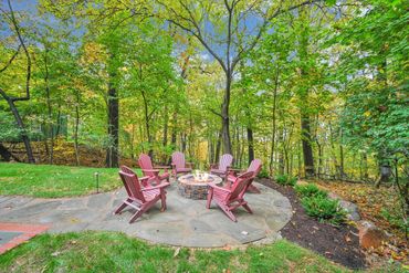 private outdoor gas firepit with Adirondack chairs in a wooded setting at a vacation rental home