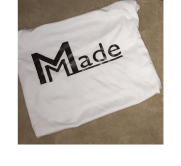 White fabric with the word 'Made' printed in black, featuring a stylized 'M'.