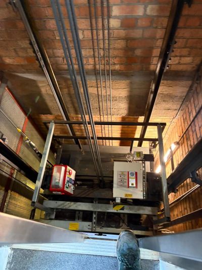 Lift car top, controller and ropes inside a brick lift shaft during a LOLER thorough examination