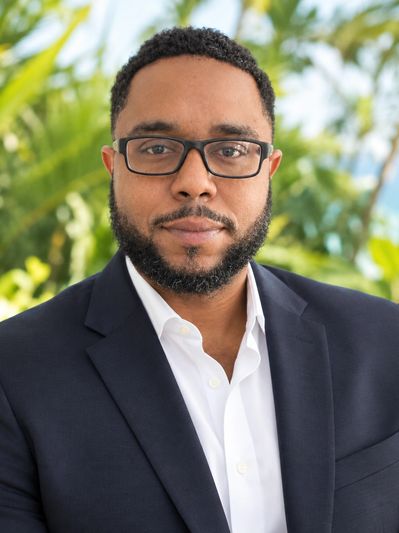 Man in suit with glasses outdoors.