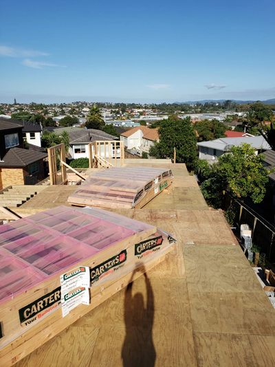 Construction site with plywood sheets and building materials under a clear blue sky.