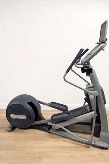 Modern elliptical exercise machine on wooden floor against white wall.