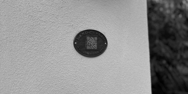 Black and white photo of a QR code plaque on a textured wall.
