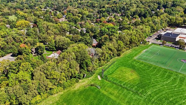Aerial view of green fields and wooded residential area.