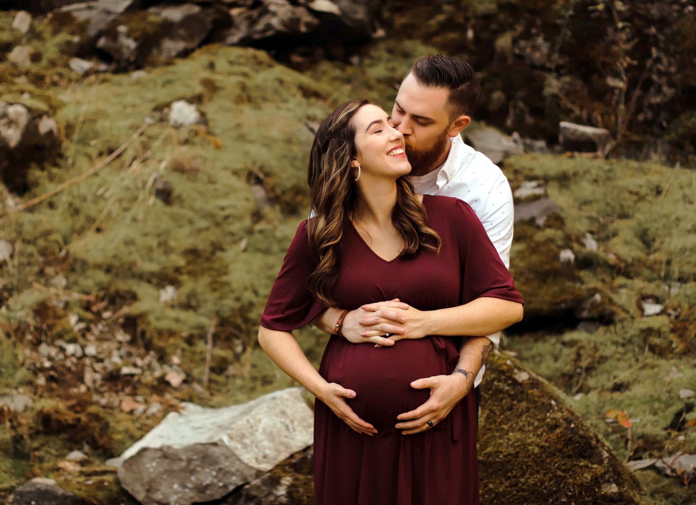 Pregnant woman and partner share a loving embrace outdoors.