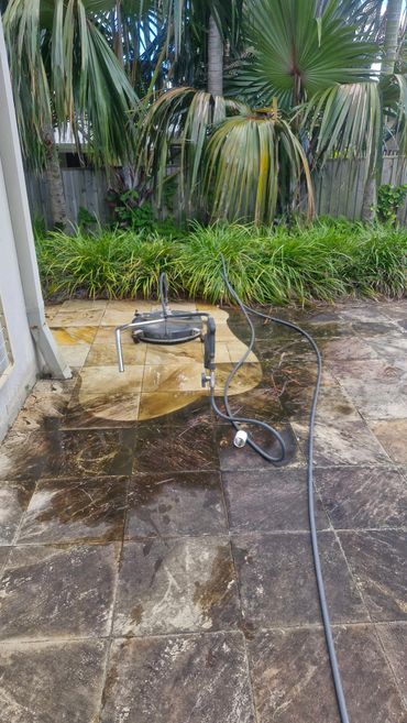 Pressure washing outdoor tiles, showing cleaned and dirty sections.