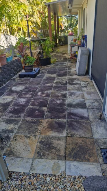 Outdoor patio with weathered tile flooring and potted plants under a covered walkway.