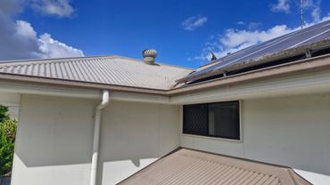 Modern house roof with solar panels under a bright blue sky.
