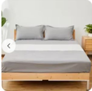 Minimalist bed setup with gray pillows and bedding on wooden frame for health benefits grounding
