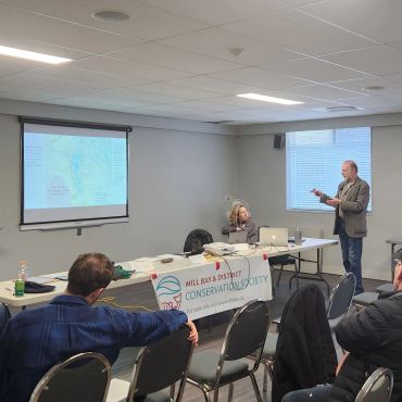 Man giving presentation to a small audience in a conference room.