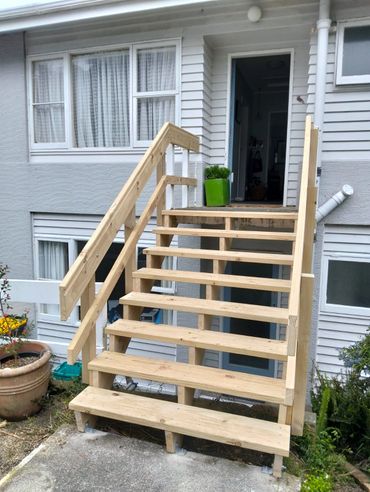 Newly built wooden stairs leading to a house entrance.