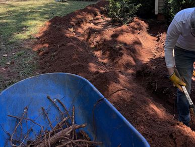 Man digging in a garden near a house with equipment visible.