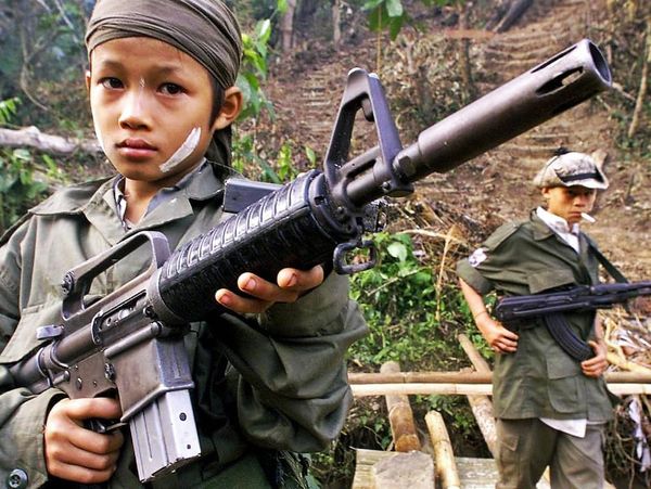 Kindersoldaten met wapens in een bosrijke omgeving.