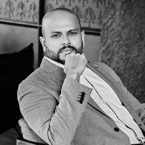 Confident man in a suit posing thoughtfully in black and white.