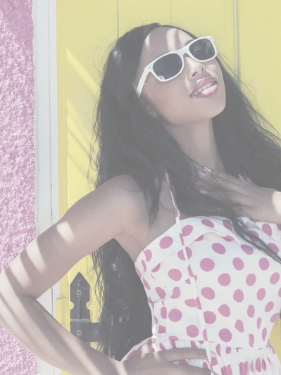 A happy young woman wearing a pink polka-dot dress and sunglasses