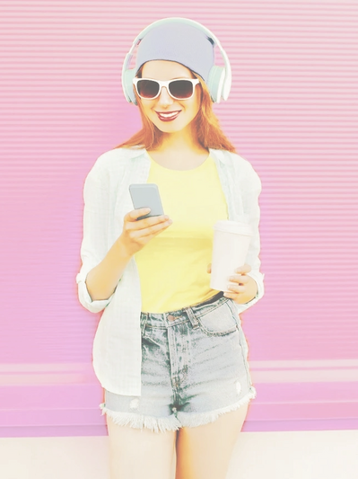 A trendy young woman is booking an eyebrow appointment online from her phone while enjoying a drink.
