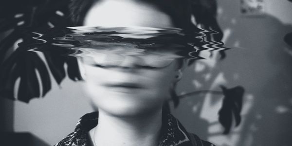 Black and white portrait with distorted face effect, blurring the eyes and nose area.