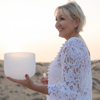 Woman holding a crystal bowl outdoors at sunset.