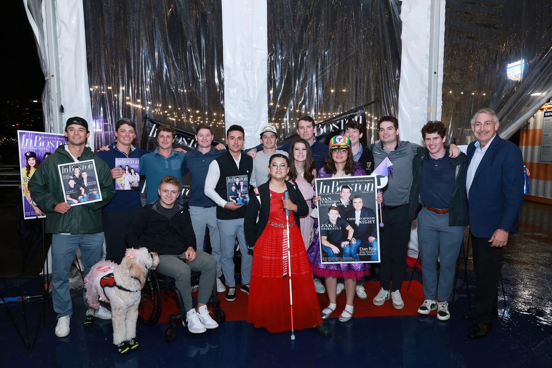 Group of people holding InBoston magazines at an event.