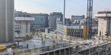 Construction site with workers and cranes under clear sky in an urban area.