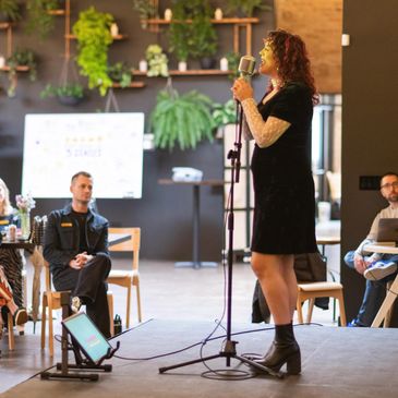 Woman speaking into a microphone at an indoor event.