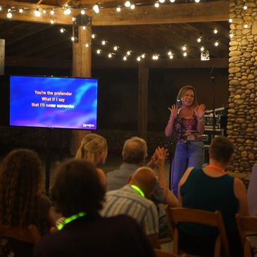 Woman singing karaoke in front of an audience at night.