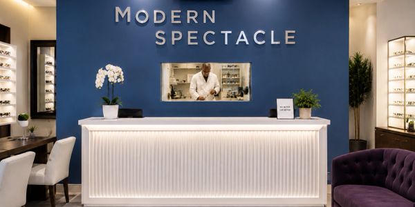 Modern spectacle eyewear store with a sleek white counter and blue accent wall.