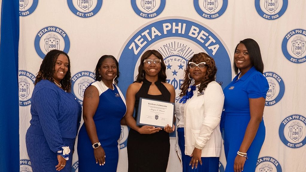 Five women posing at a Zeta Phi Beta event, one holding a certificate.