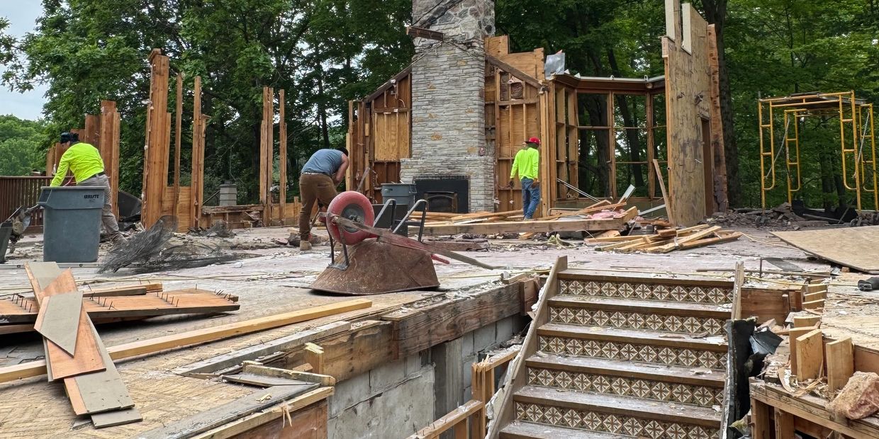 Workers demolishing and clearing a partially stripped house.