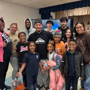 A diverse group of adults and children smiling indoors.