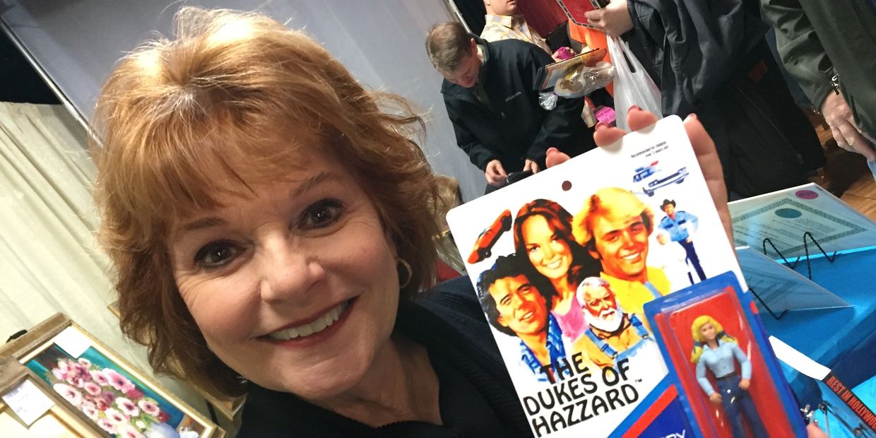 Dorothy Best holding an action figure of her character from the Dukes of Hazzard.