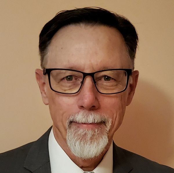 Portrait of a man with glasses and white beard.