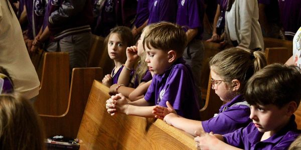 Children in purple shirts sitting in church pews.