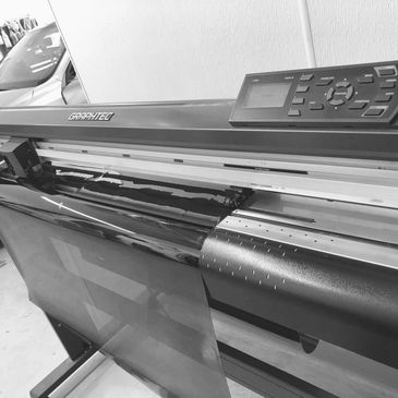 Large Graphtec cutting plotter with vinyl roll in a workshop.