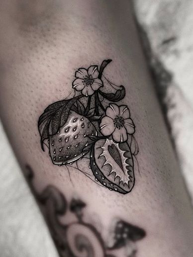 Black and white neotrad strawberry tattoo with flowers on skin.