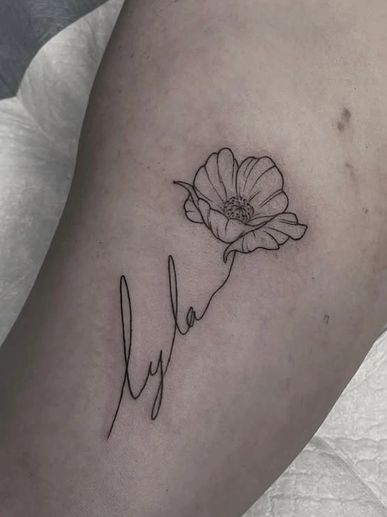 Delicate fine line tattoo of the name 'Lyla' blending into a flower design on the skin.