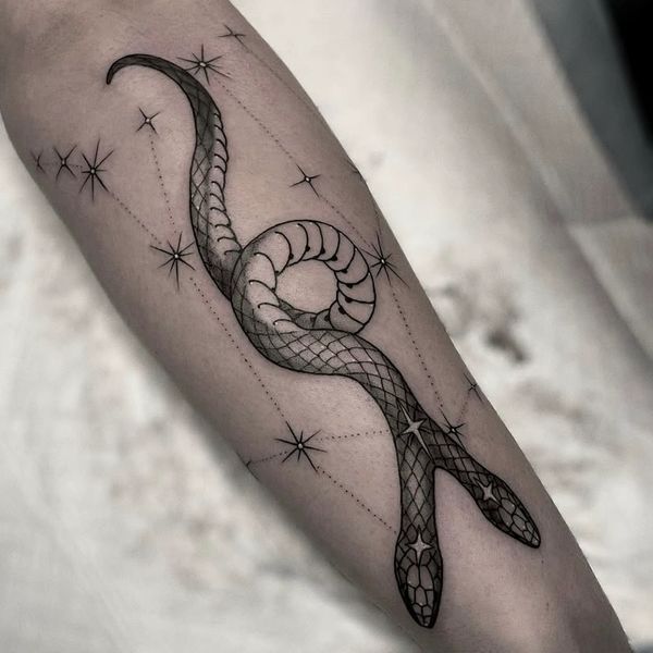 Black and grey snake tattoo intertwined with star-like dots on forearm.