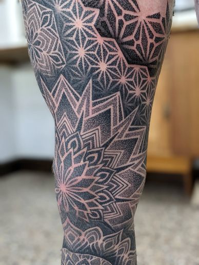 Intricate geometric tattoo with star and mandala patterns on skin.