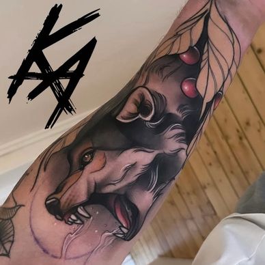 A detailed neotrad tattoo of a wolf's head with leaves and red berries on a person's forearm.