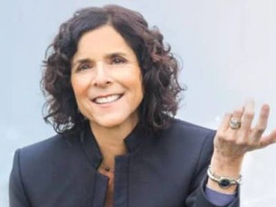 Smiling woman with curly hair wearing a dark blazer.