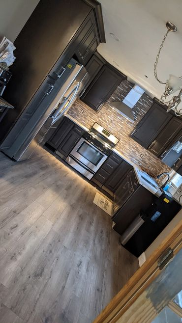 modern kitchen feat dark cabinetry, stainless steel appliances, and tile backsplash, upscale look.