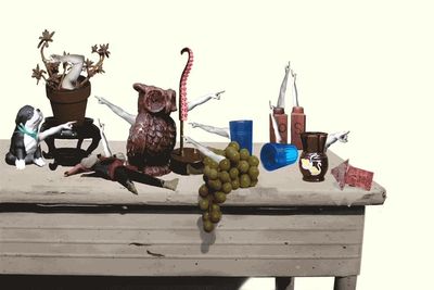 A table with various objects and pointing hands.