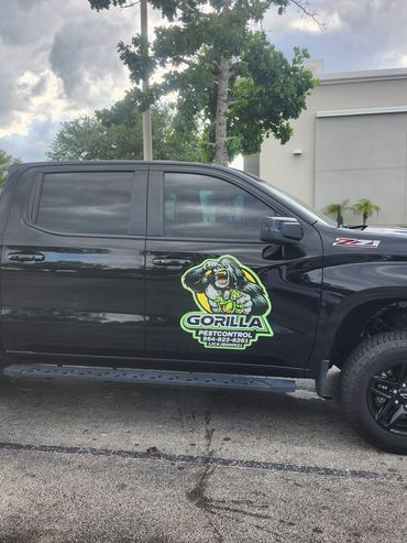 Black pickup truck with Gorilla Pest Control logo parked near a stop sign.