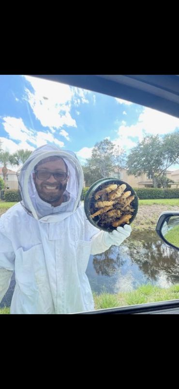 A beekeeper shows a container with bee larvae near a pond.