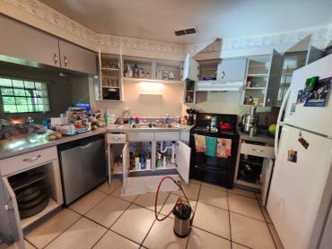 Kitchen with open cabinets and drawers, and a tool on the floor.