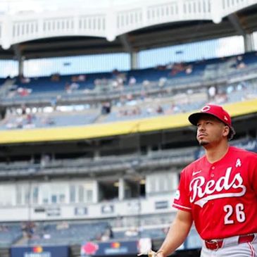 Baseball player in Cincinnati Reds uniform at stadium.