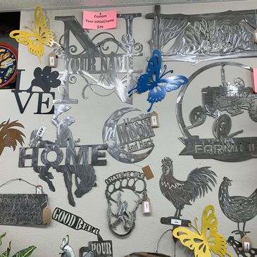 Metal wall art with various designs including butterflies, animals, and words.