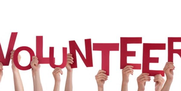 Hands holding up letters spelling 'VOLUNTEER'.