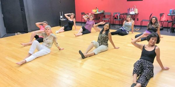 Group fitness class seated on floor saluting.
