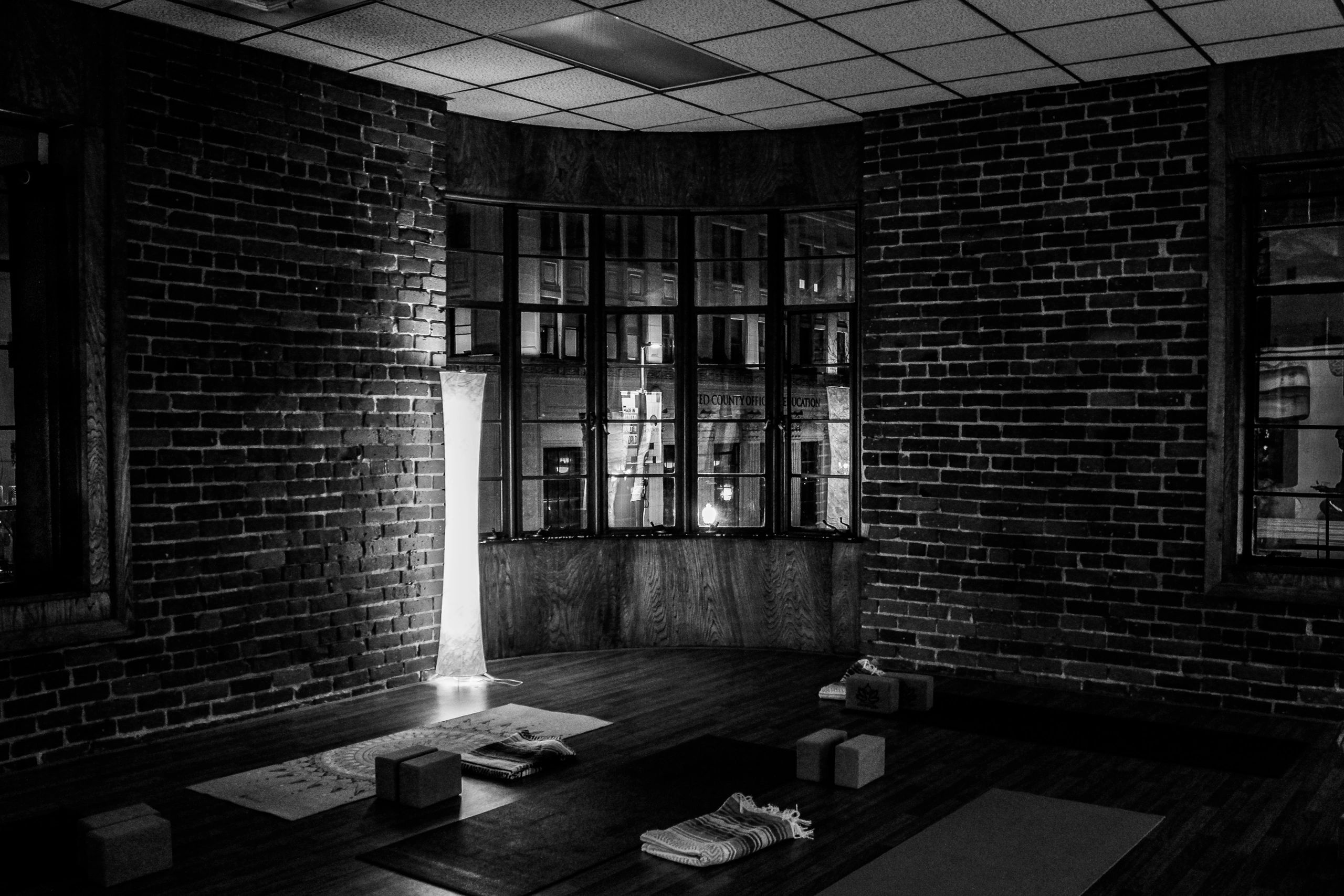 Dimly lit yoga studio with brick walls and floor lamps.